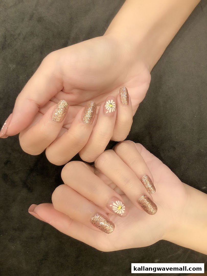 Close-up of hands showcasing glitter and daisy nail art designs.