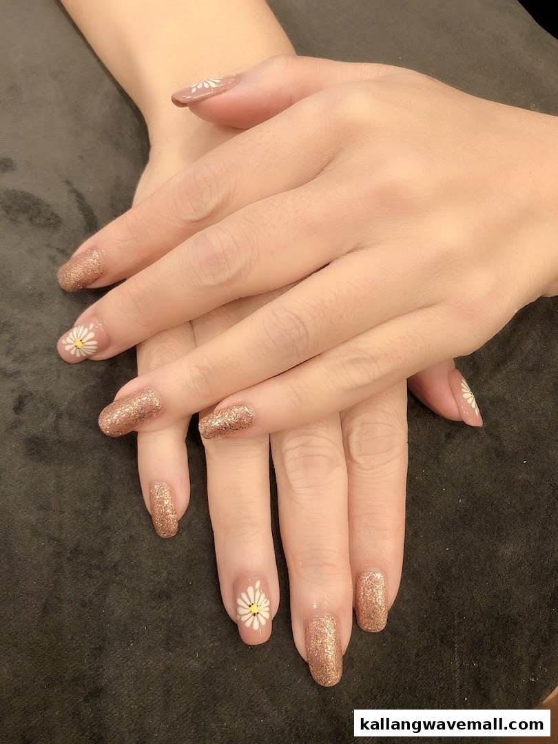 Close-up of hands showcasing beautiful glitter and daisy nail art design.