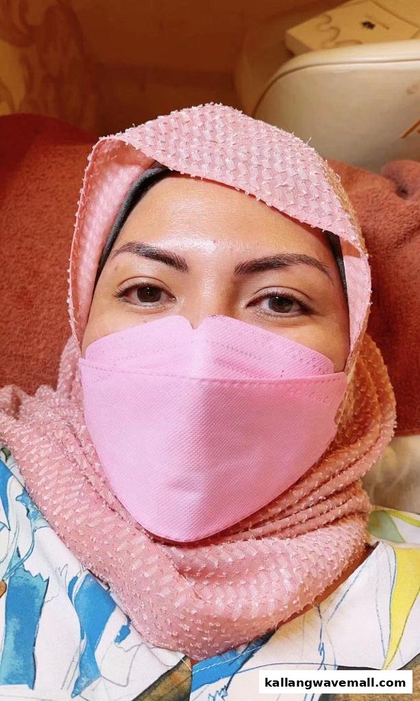 A close-up of a client wearing a pink mask and head covering, likely undergoing a beauty treatment.