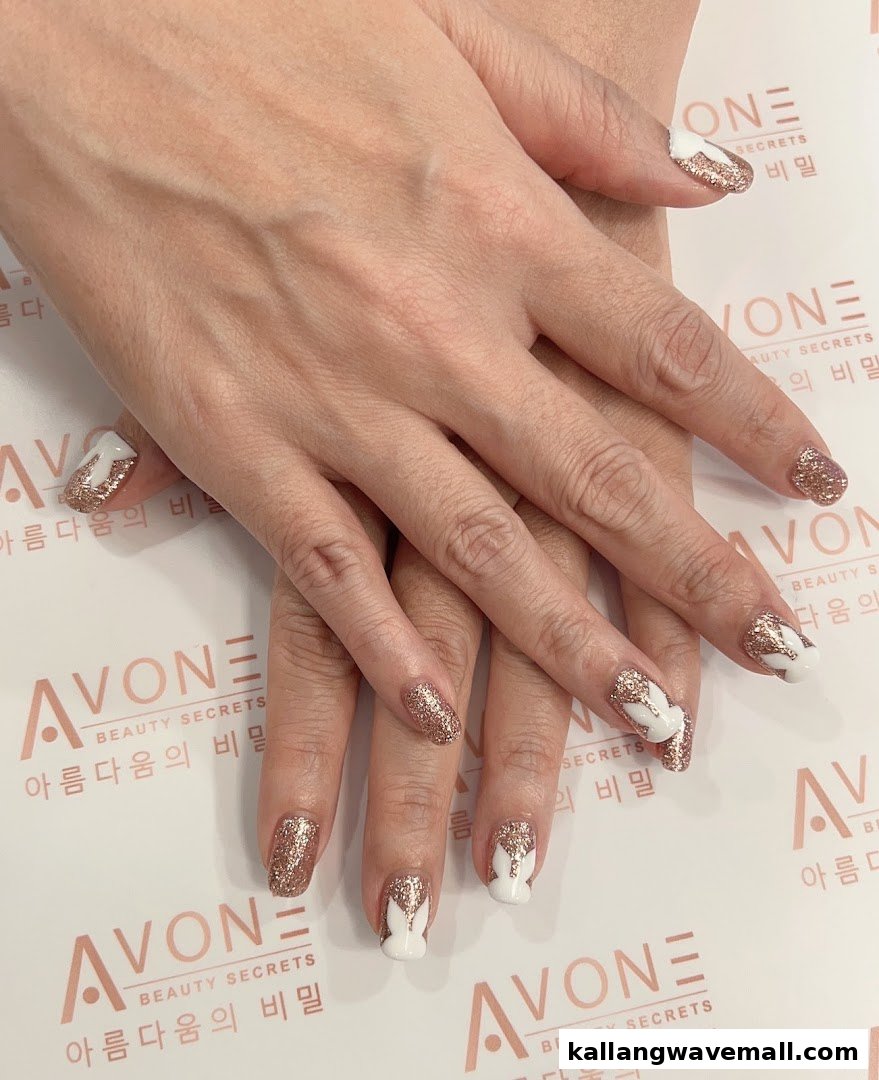 Close-up of hands showcasing elegant white and gold glitter nail art by Avone Beauty Secrets.