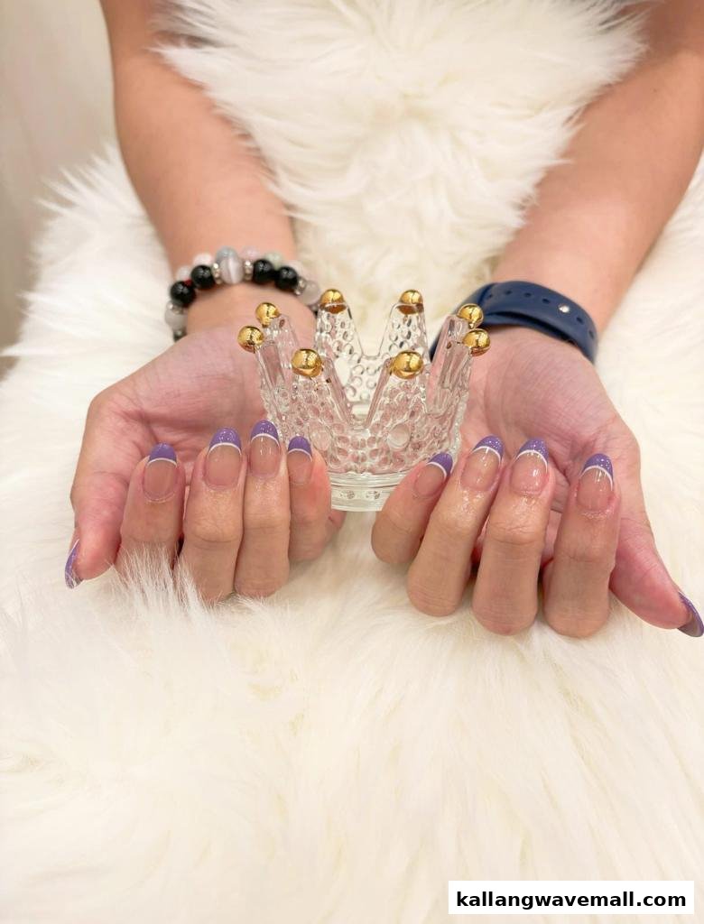 Close-up of hands with elegant purple French tip nails holding a decorative glass crown.