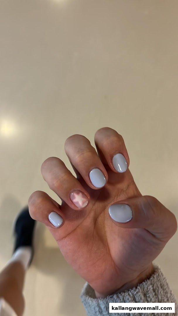A hand showcasing light blue nail polish with a delicate star design on one accent nail.