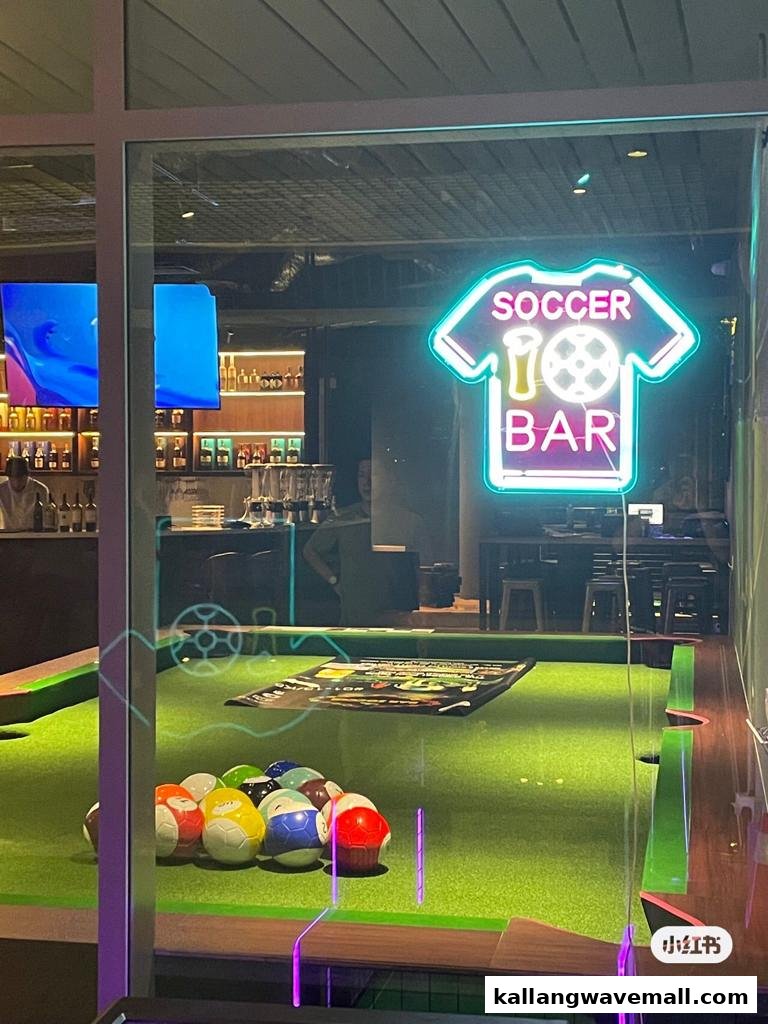 View through the glass front of Bar Soccer, showing a neon sign, bar, and soccer-themed pool table.