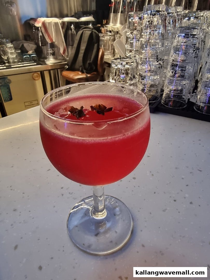 A vibrant red cocktail garnished with star anise sits on a bar counter at Bar Soccer.