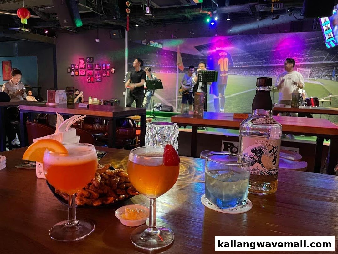 Vibrant bar interior with cocktails, snacks, live music, and a large screen showing a football match.