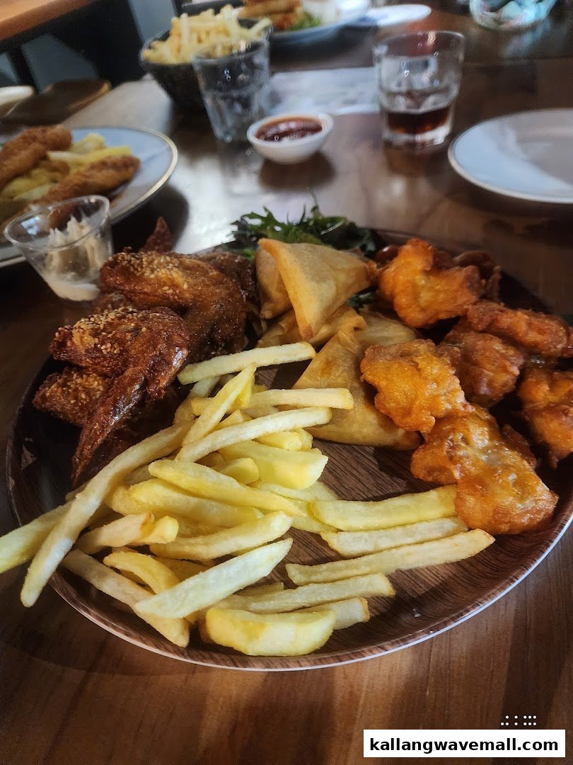 A delicious platter featuring fries, chicken wings, samosas, and battered bites, perfect for sharing.