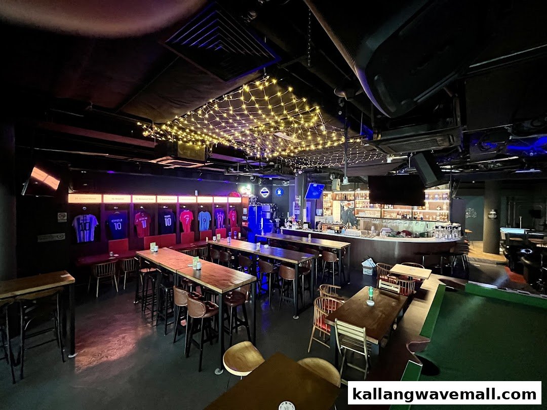 An interior view of Bar Soccer, featuring a bar, seating, and football jersey displays under string lights.