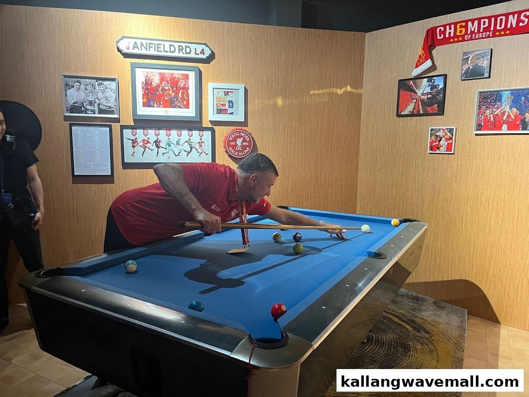 Man playing pool in a sports-themed room with football memorabilia.