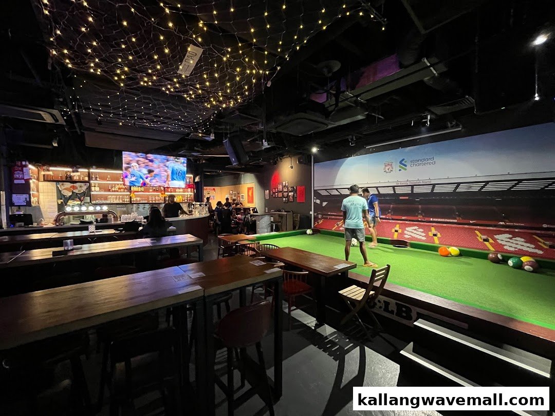 An interior view of Bar Soccer, featuring a soccer-themed pool table, a bar, and a large screen.