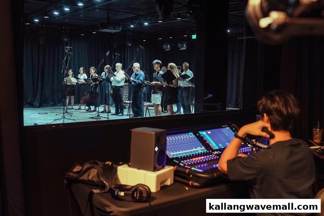 A sound engineer operates a mixing console while a vocal group performs on stage at BELLS New Media Lab.
