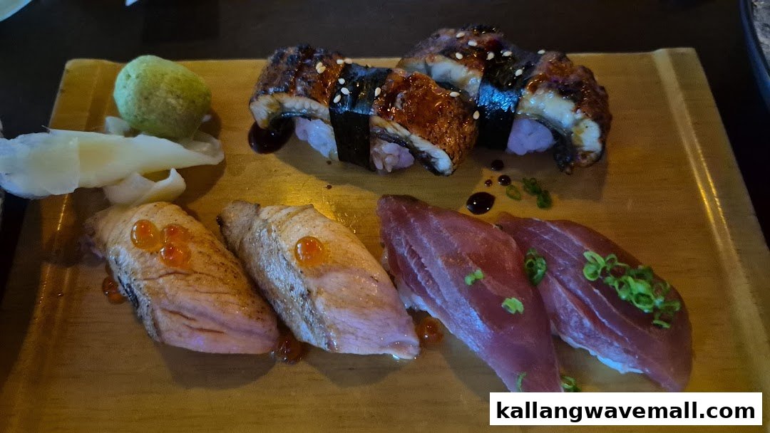 A wooden board displays various sushi and nigiri pieces, including eel, seared salmon, and tuna.