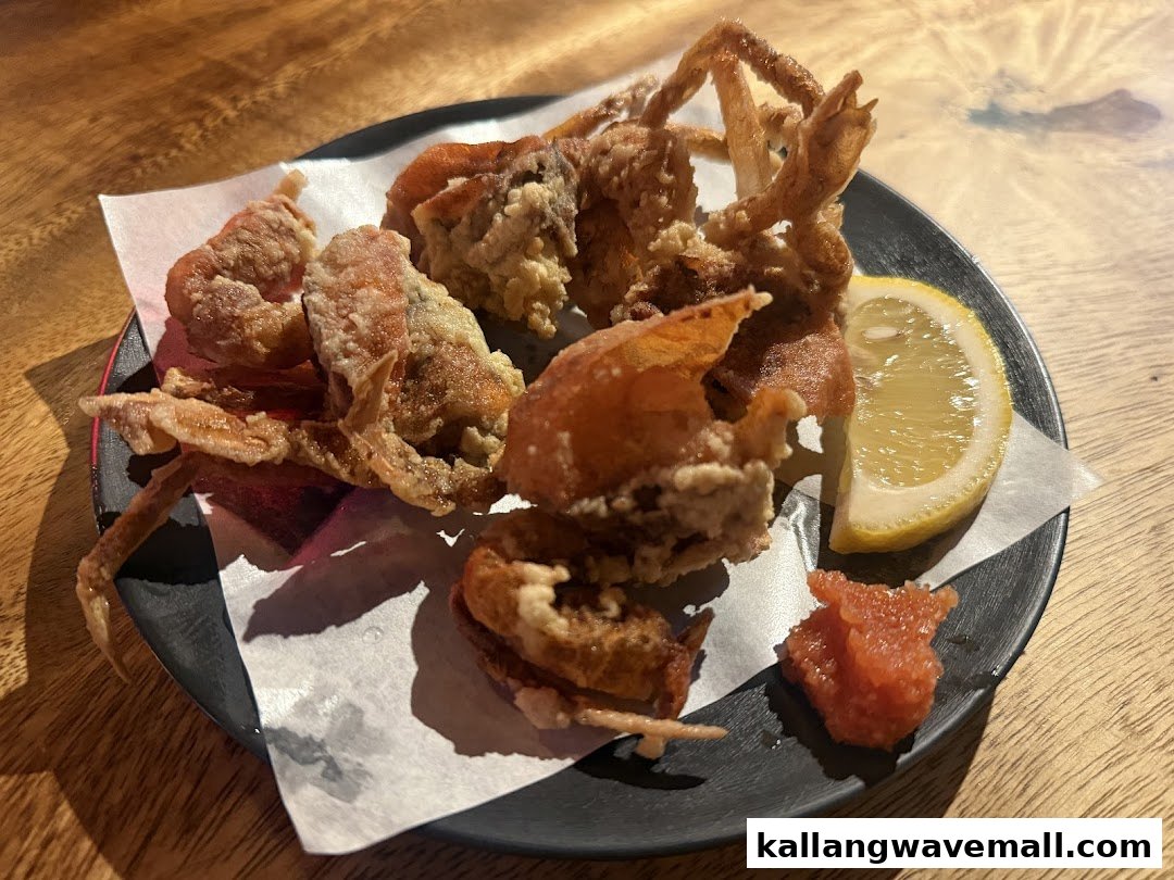 A plate of crispy fried soft-shell crab with a lemon wedge and red roe.