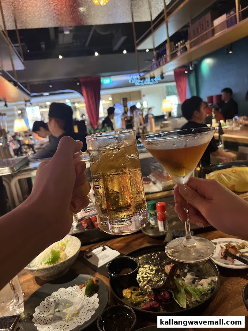 Two people toasting with drinks and food at a lively restaurant table.