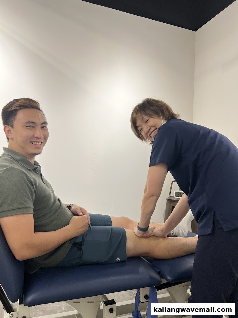 A physiotherapist treats a smiling patient on an examination table.