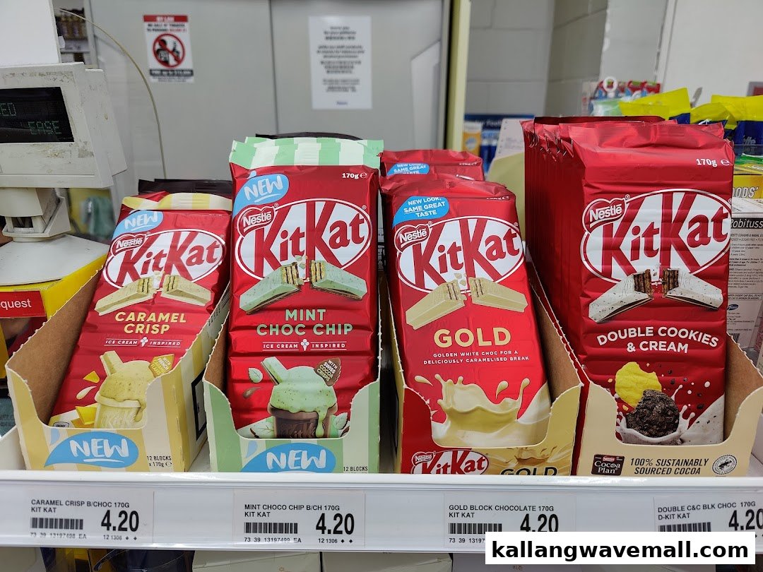 A display of various Kit Kat chocolate bar flavors, including Caramel Crisp, Mint Choc Chip, Gold, and Double Cookies & Cream, with prices.