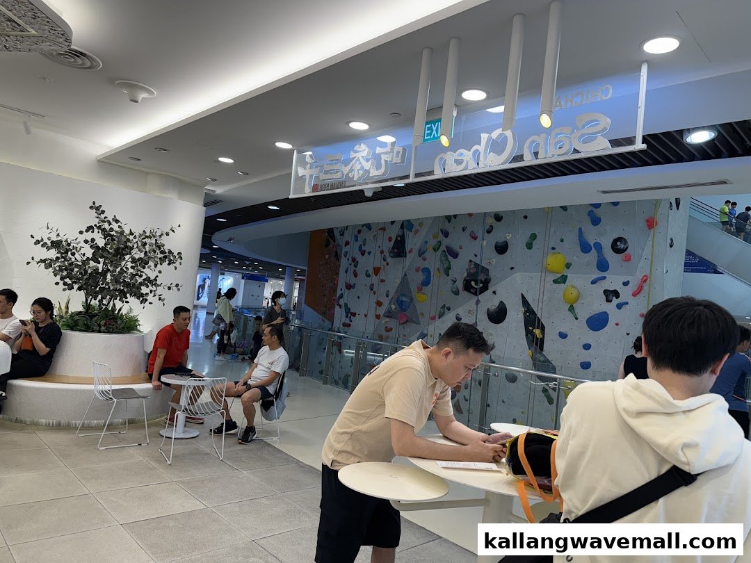 People relaxing in a modern mall setting near a climbing wall, with the CHICHA San Chen sign visible.