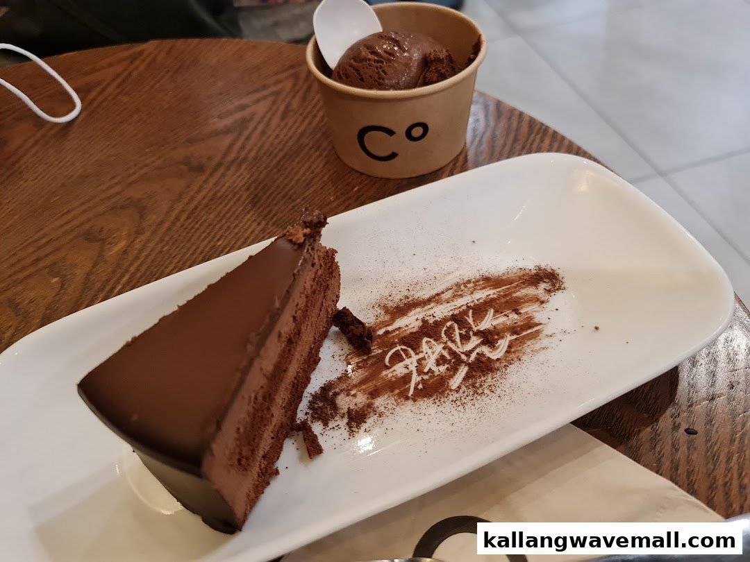 A rich chocolate cake slice and chocolate ice cream on a wooden table.