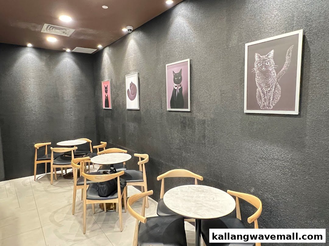 Cozy cafe interior with dark walls, modern tables, and charming cat artwork.