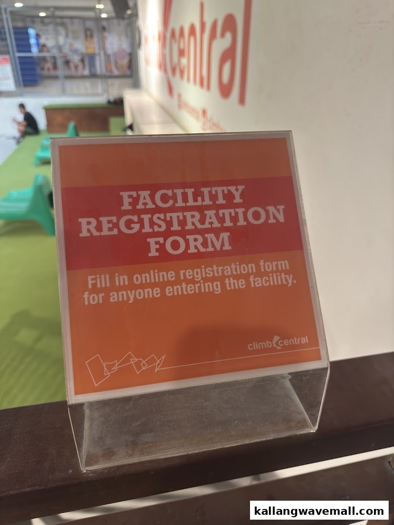 A sign for facility registration at Climb Central, with the gym interior visible in the background.