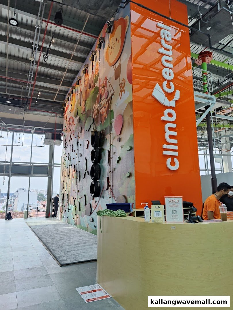 An indoor climbing gym featuring a colorful wall with cartoon graphics and a reception area.