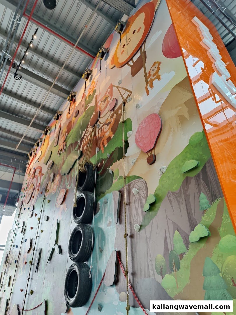 A vibrant indoor climbing wall featuring cartoon illustrations of monkeys and hot air balloons, with various climbing holds.