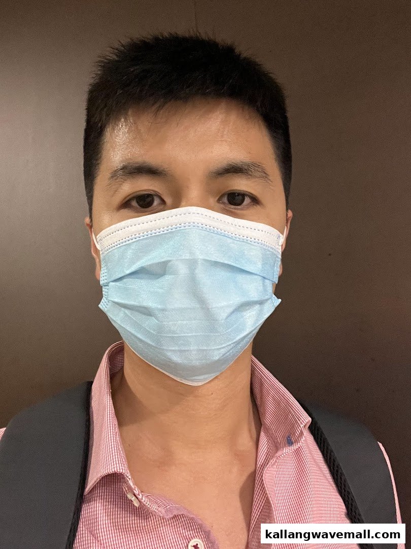 A person wearing a light blue surgical mask, looking directly at the camera.