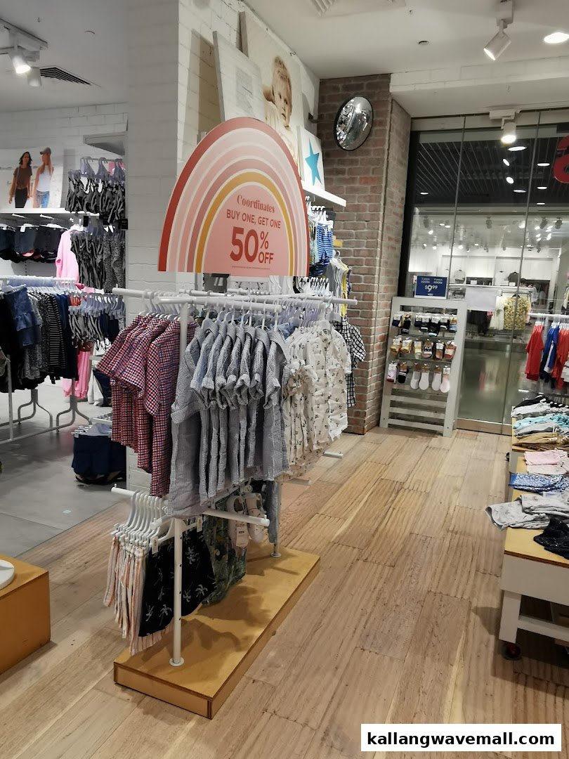 Interior view of Cotton On Sports Hub, featuring clothing racks with children's apparel and a 'Buy One, Get One 50% Off' sign.