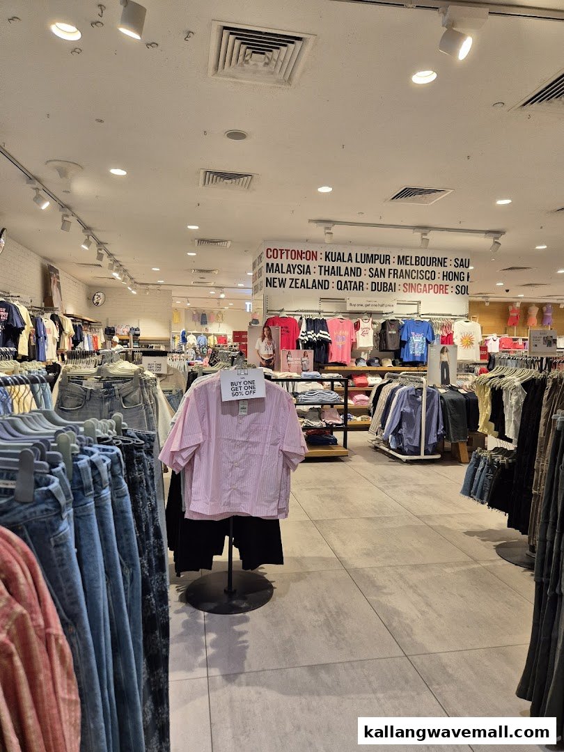 An interior view of Cotton On Sports Hub, showcasing various clothing racks, denim, and a prominent sign listing global locations.