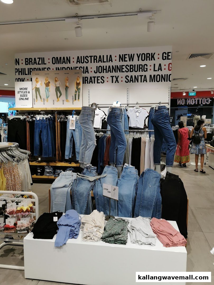 An interior view of Cotton On Sports Hub, showcasing a wide selection of denim jeans and casual apparel on display.