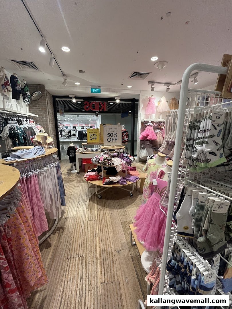 Interior view of Cotton On Sports Hub's kids' clothing section, featuring racks of apparel and 50% off sale signs.