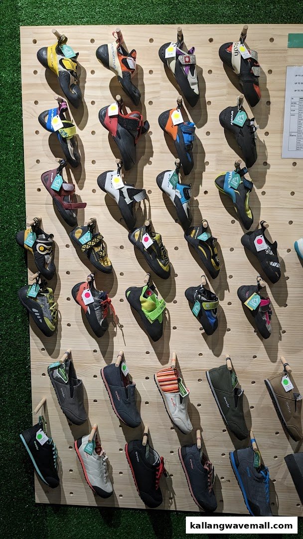 A display wall showcasing a wide variety of colorful climbing and approach shoes at Crank Factory.