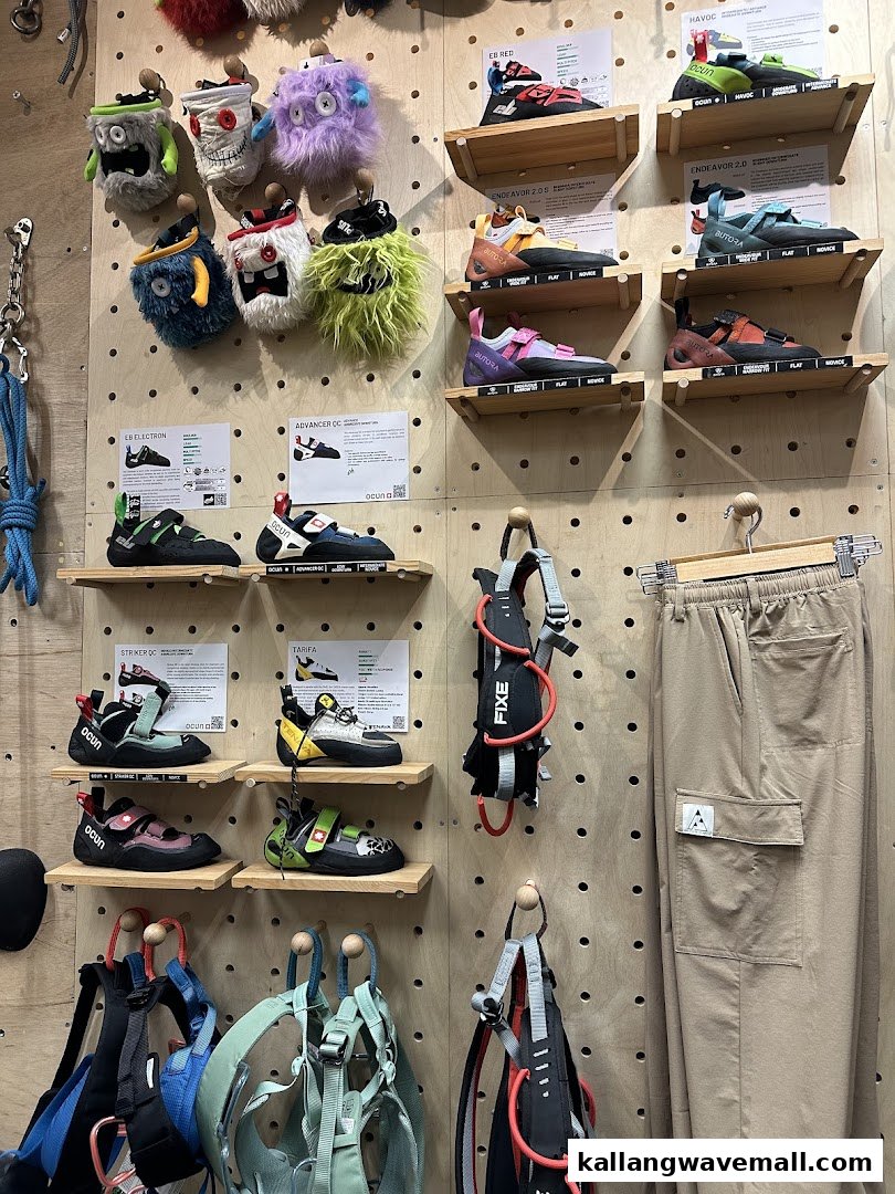 A pegboard wall display showcasing a variety of climbing shoes, chalk bags, harnesses, and apparel.