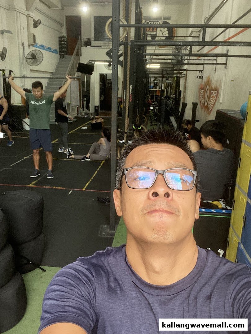People exercising in a CrossFit gym, featuring various fitness equipment and a participant's selfie.