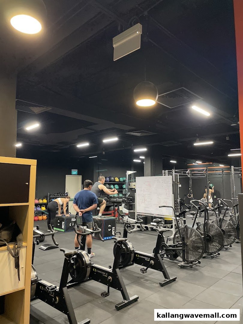 People engage in various exercises with fitness equipment inside a modern CrossFit gym.