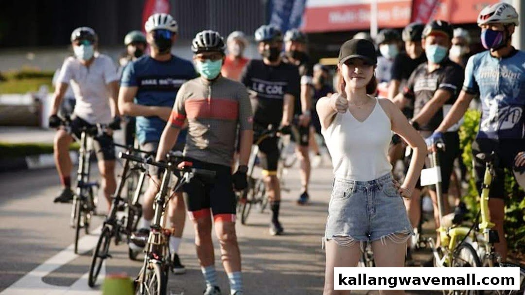 A group of cyclists, some masked, pose with their bikes outdoors, one giving a thumbs-up.