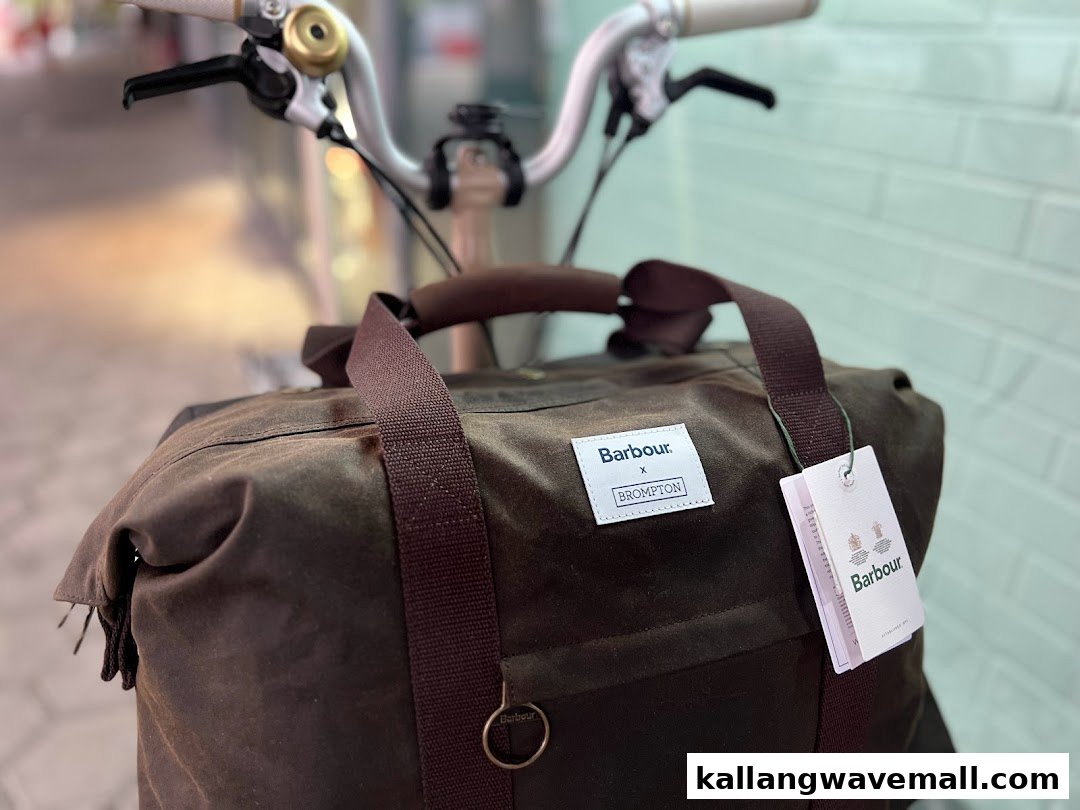 A close-up of a Barbour x Brompton collaboration bag attached to a bicycle handlebar.