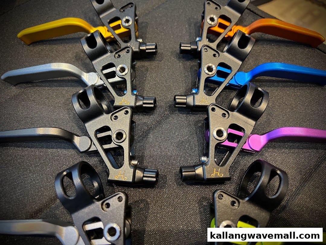 Close-up of colorful bicycle brake levers and components displayed on a dark surface.