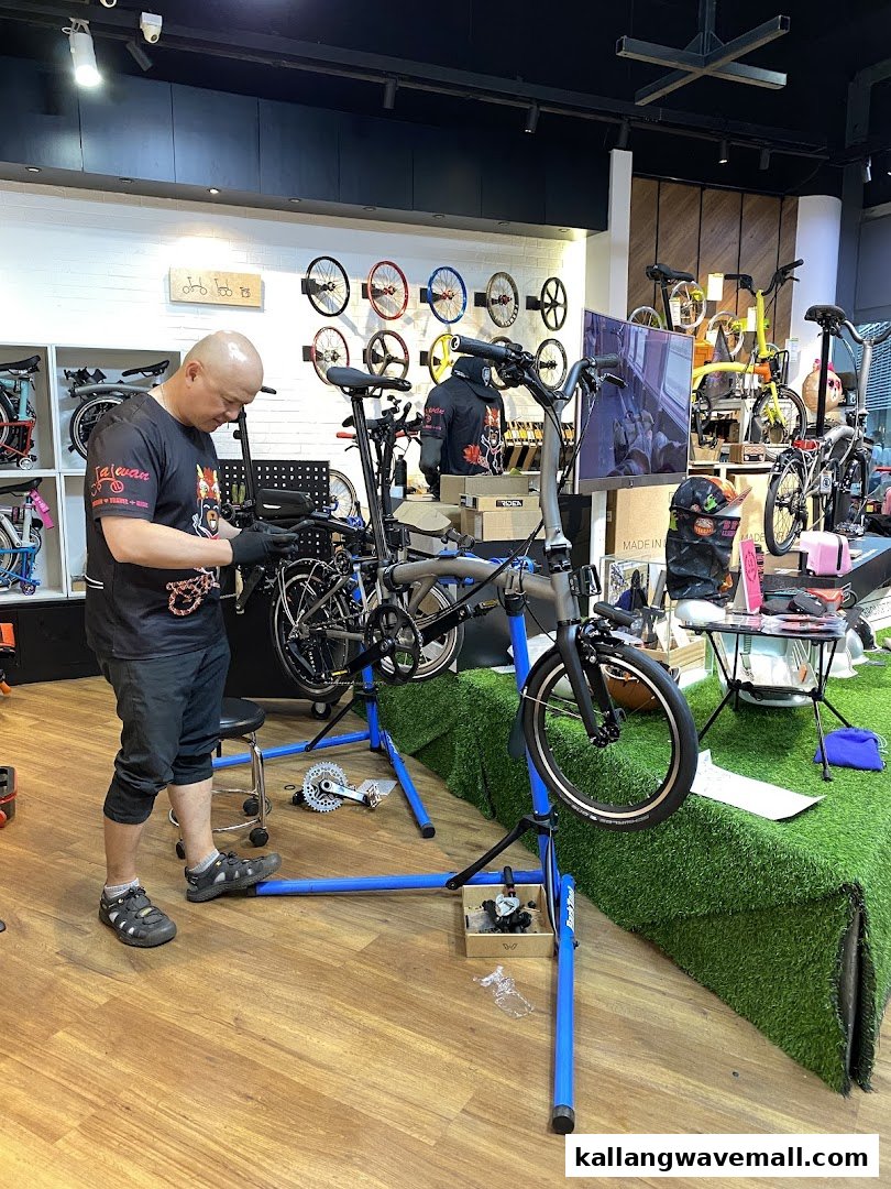 A mechanic works on a bicycle in a well-equipped bike shop, surrounded by bike parts and accessories.