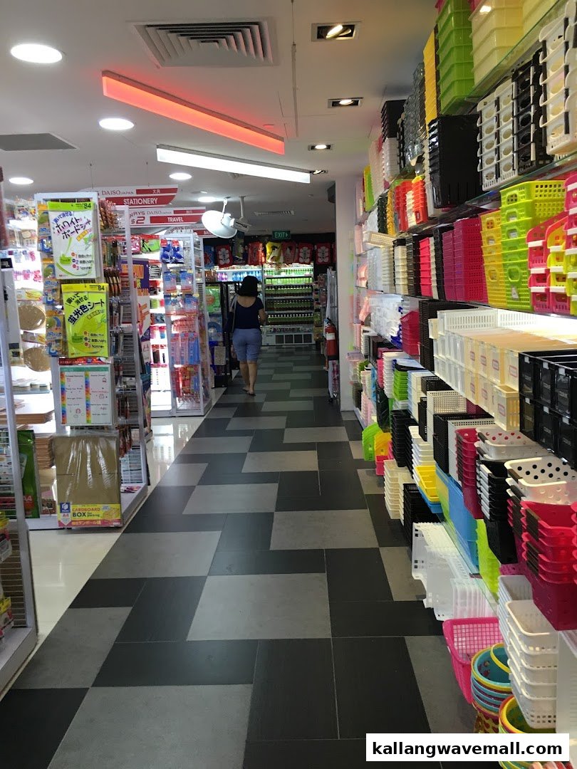 A customer walks through a brightly lit Daiso aisle filled with colorful storage solutions and stationery.