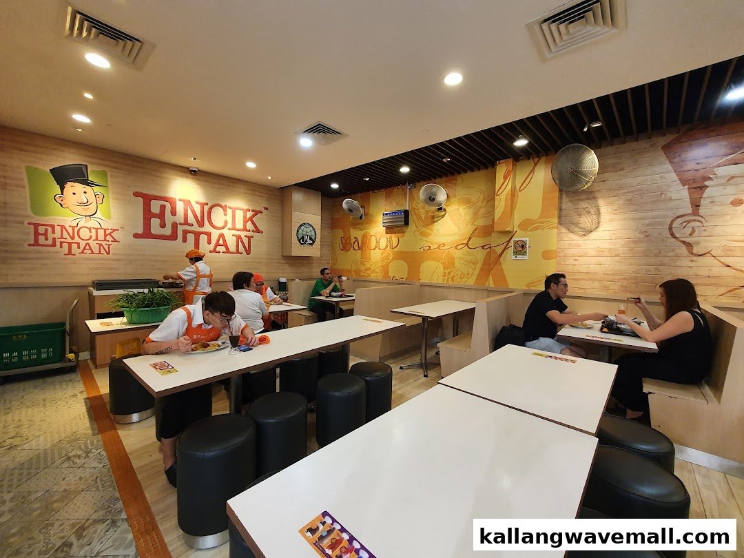 Customers enjoy meals in the vibrant interior of Encik Tan, featuring a large brand logo and lively decor.