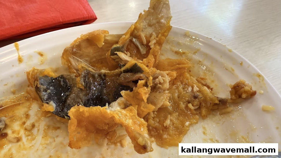 A close-up of a white plate with leftover fish bones and sauce after a meal at Encik Tan.