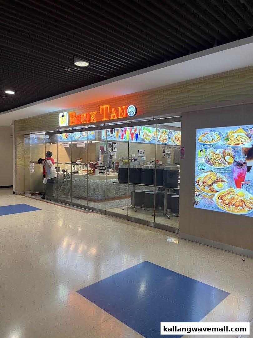 Exterior view of Encik Tan, a food stall with a bright orange sign and digital menu displays.