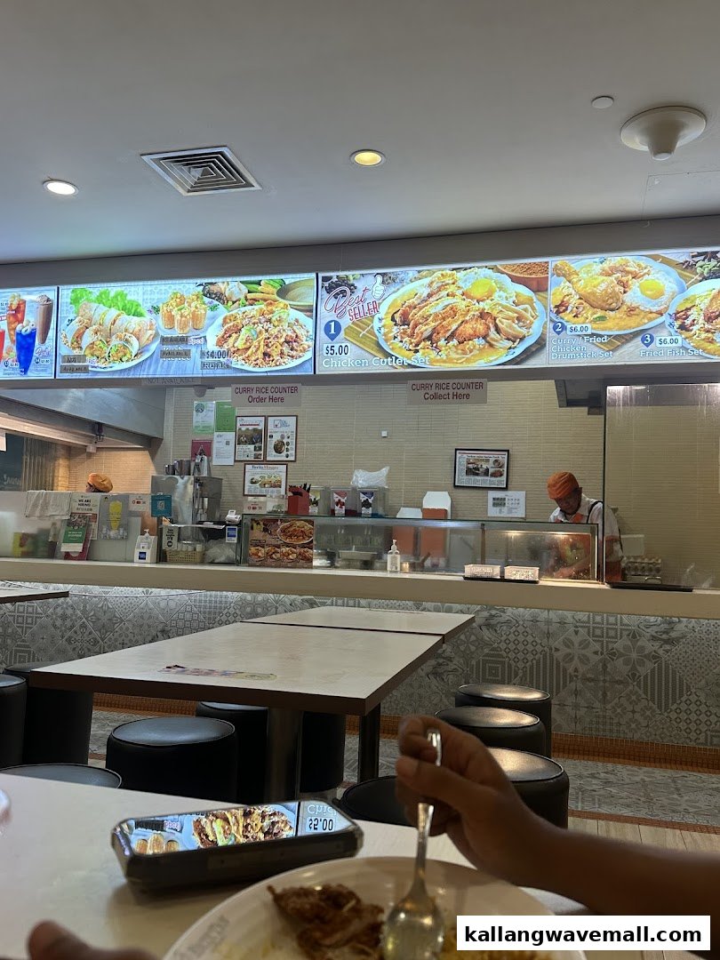 An interior view of Encik Tan, showing the food counter, menu boards, and a customer dining.