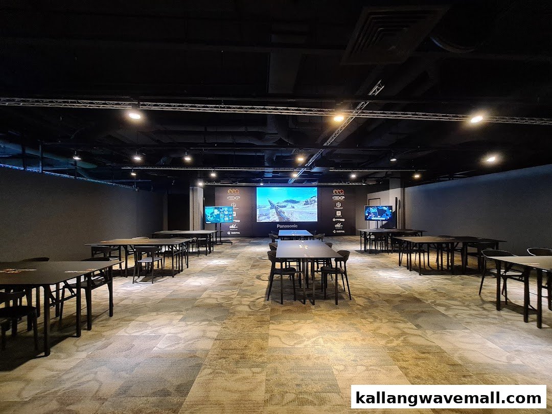 An interior view of the Esports Experience Center featuring multiple tables, chairs, and large screens for gaming.