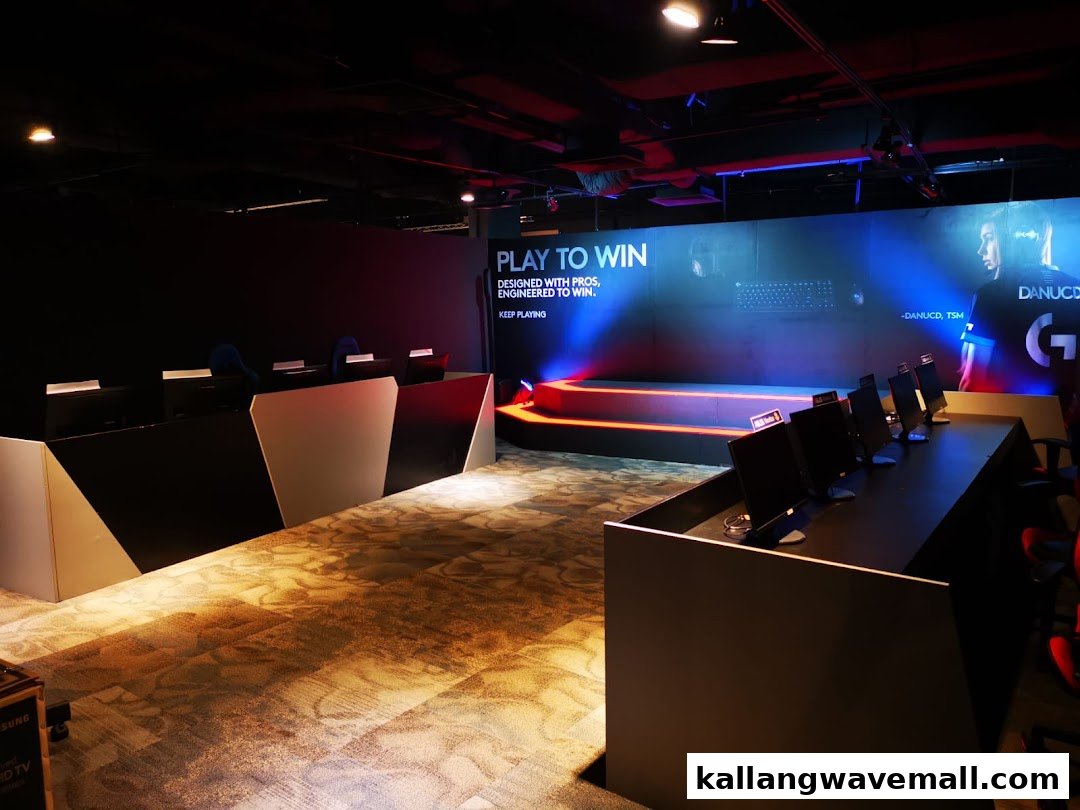 An esports gaming center interior with multiple gaming stations, a stage, and a large screen displaying 'PLAY TO WIN'.