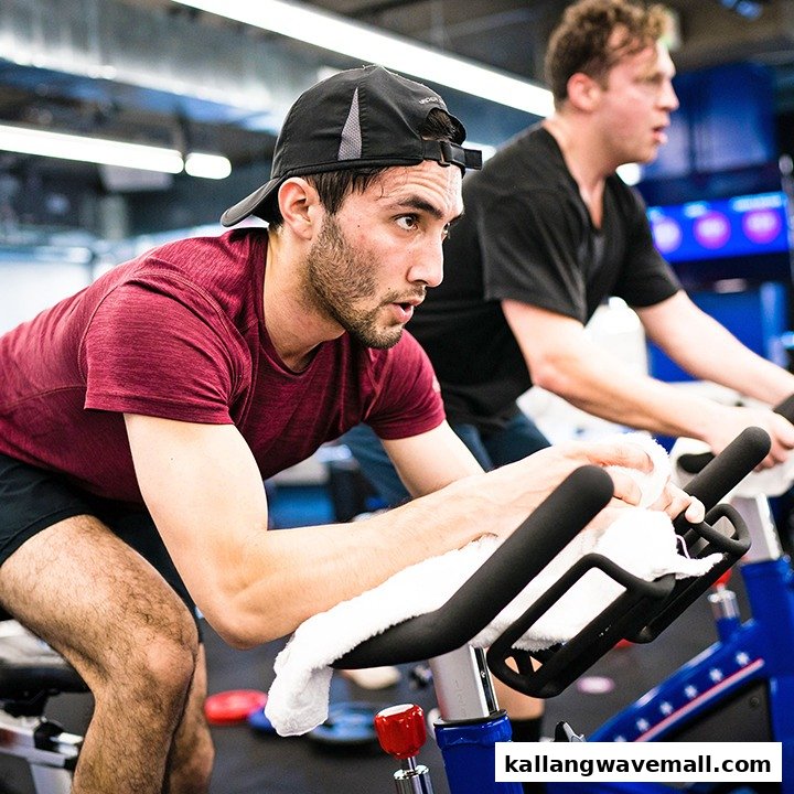 Two men intensely cycling on stationary bikes during a fitness class at F45 Training.