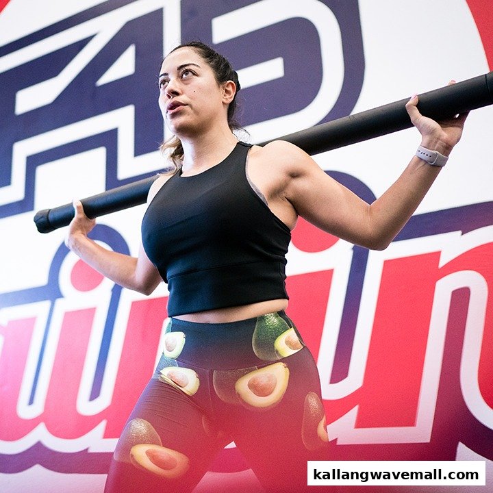 A woman performs an exercise with a fitness bar inside an F45 Training studio.