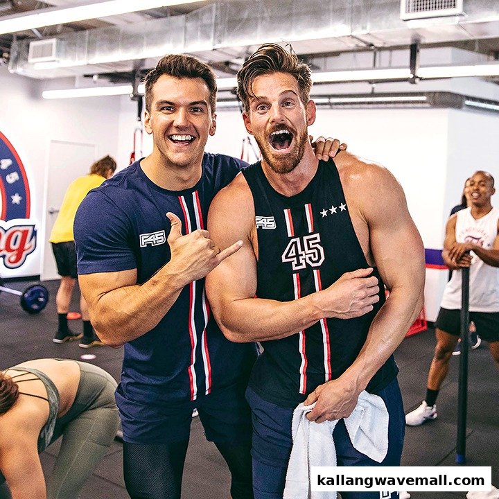 Two enthusiastic men posing in an F45 Training gym with other members in the background.