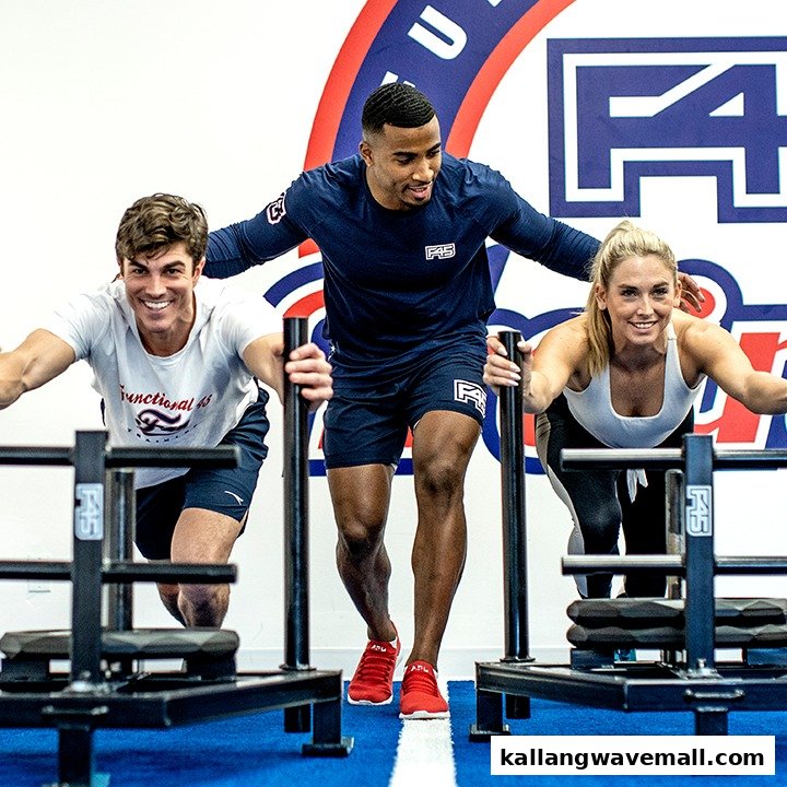 Trainer guiding two individuals performing sled pushes in an F45 Training gym.