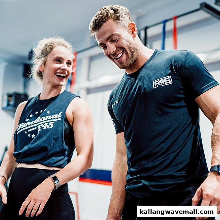 Two smiling individuals in F45 Training gear, enjoying a workout session.